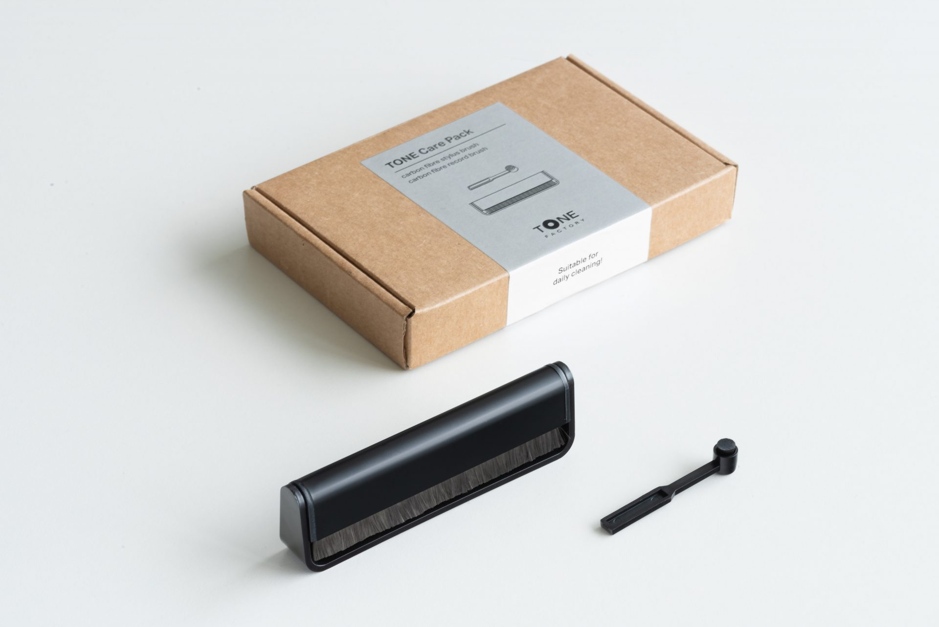 Tone Care pack, black stylus brush, black record brush on white table, brown paper box