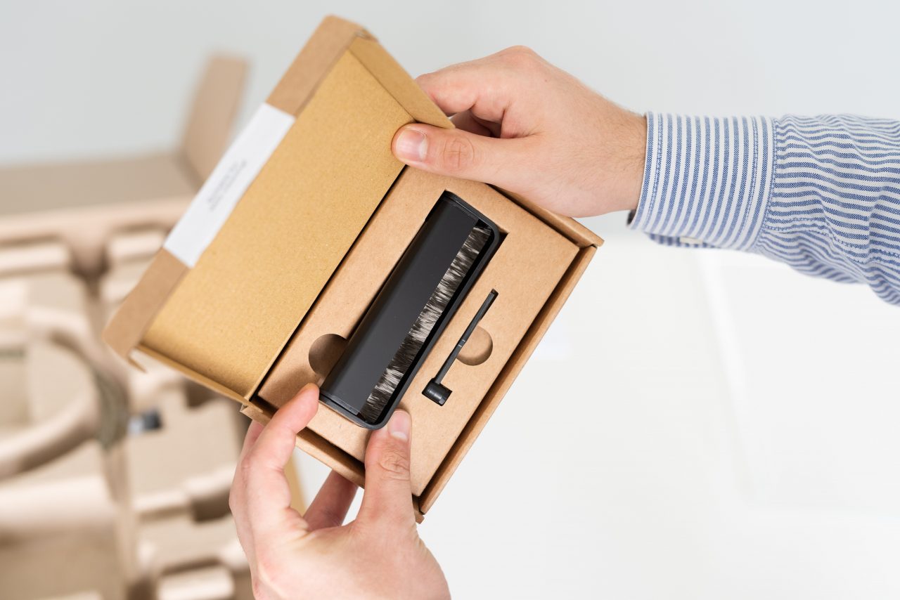 Tone Care pack, black stylus brush, black record, brush, two hands holding a brown paper box