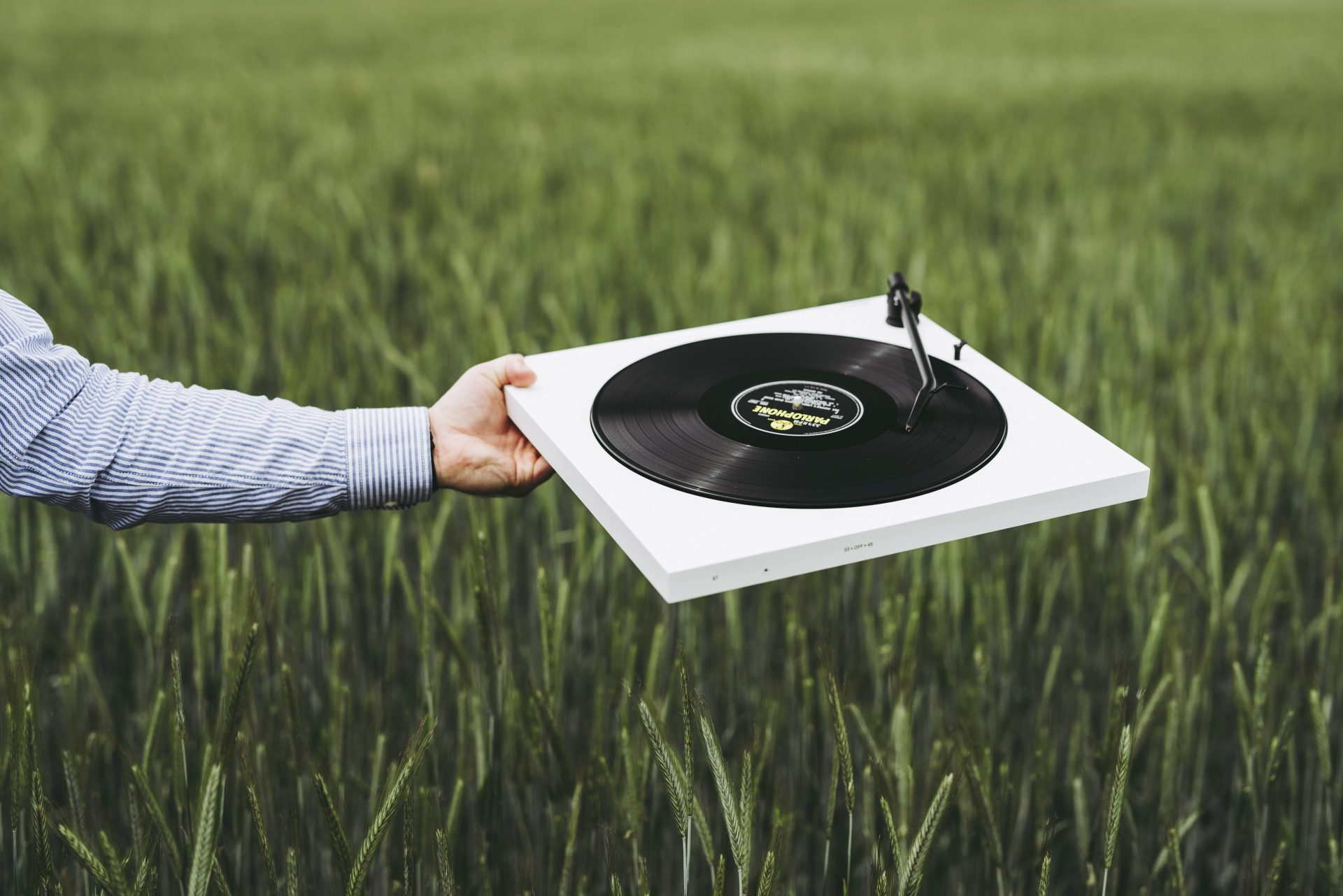 TONE turntable white holding it in front of a field