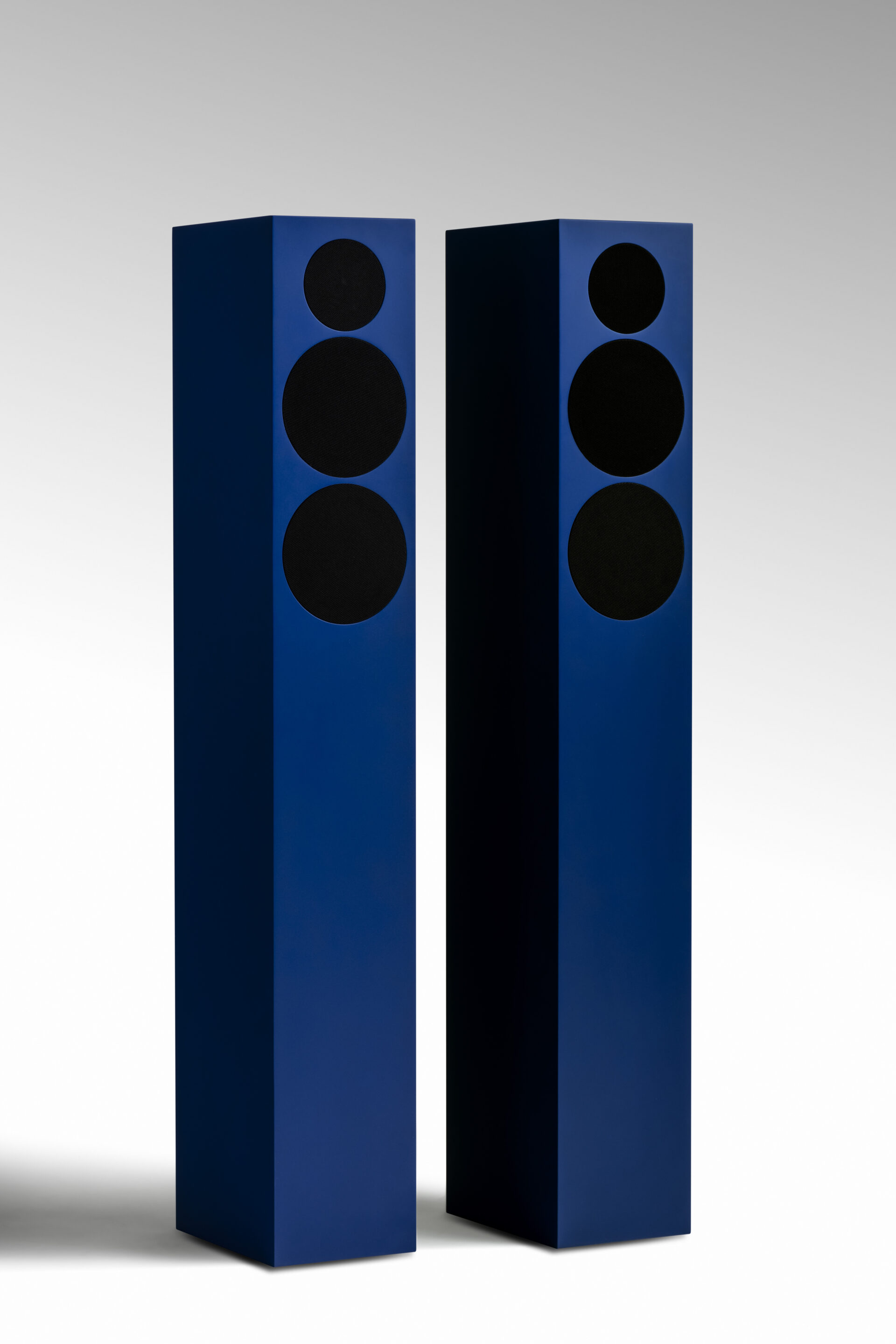 One pair of TONE Speaker L, standing in a white room on the floor. Both speakers are ultramarine blue and displayed from the frontside.